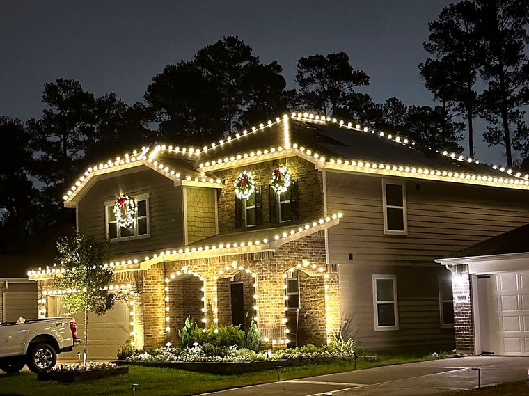 Two-story home with warm white lights on every roofline and window