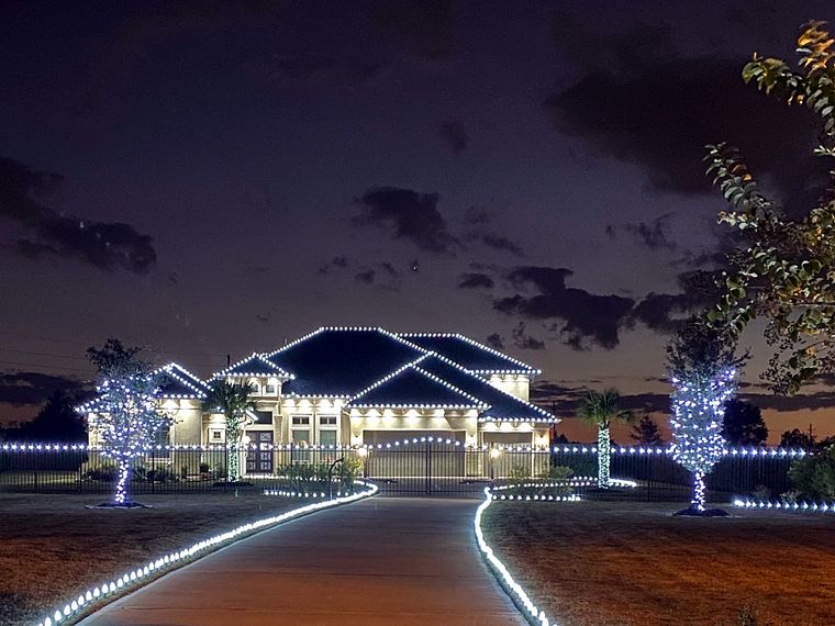 Long driveway lined with lights leading to a fully lit home