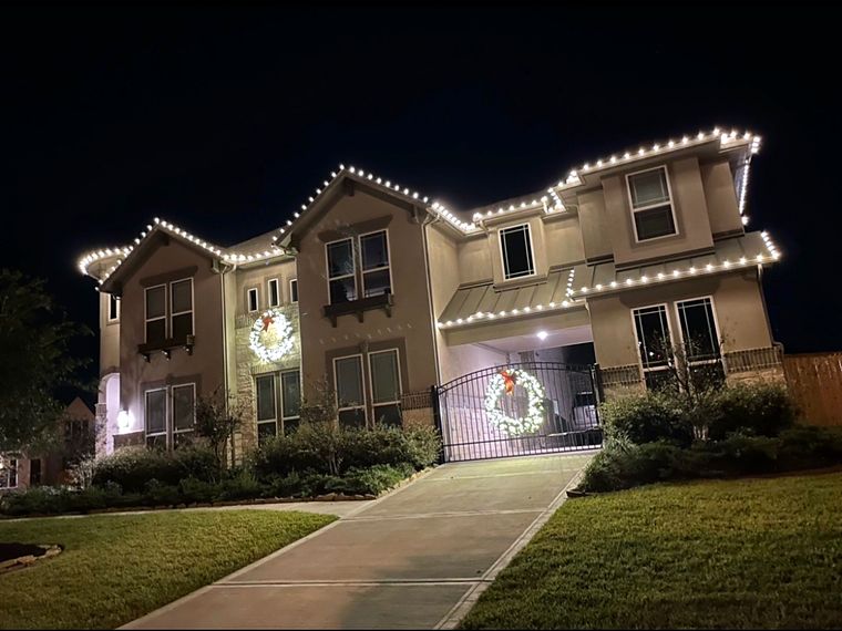 Two-story home with roofline lights and lit wreaths