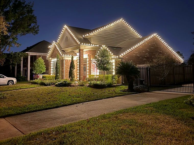 Brick home with warm white lights along every roof peak